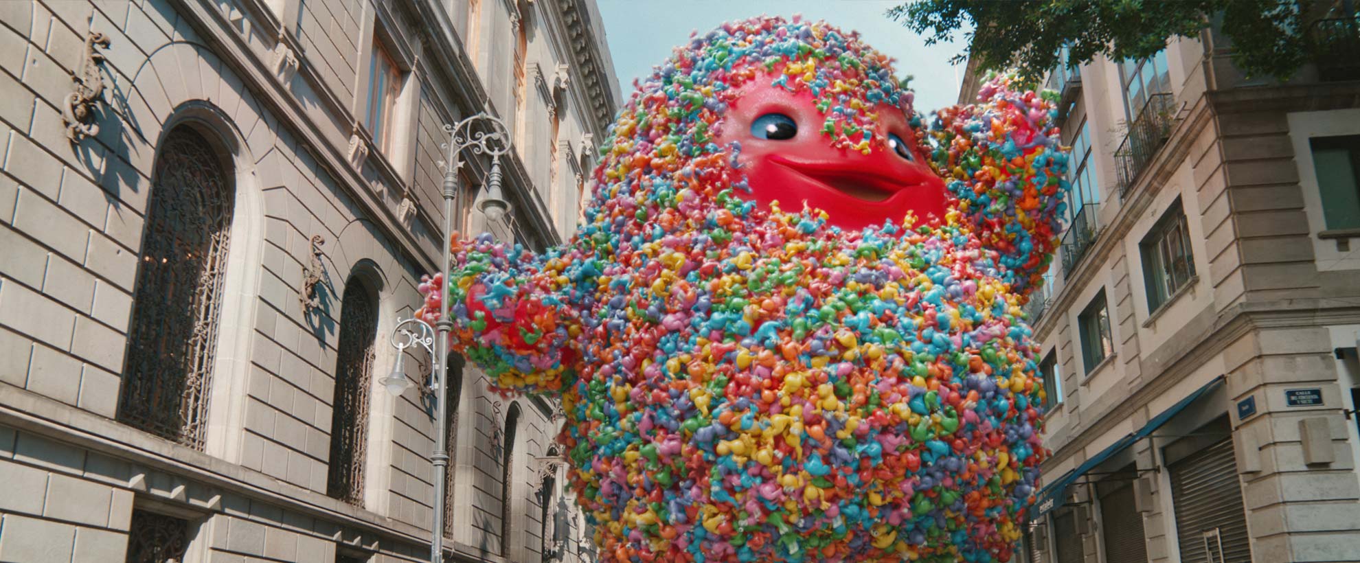 A giant gummy monster walks through a city with hundreds of nerds candy attached to it