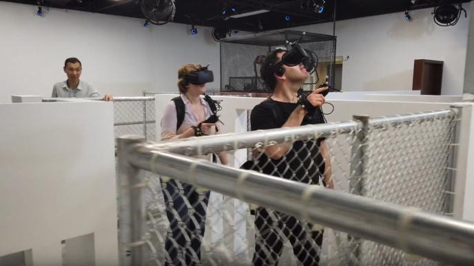 two people wearing headsets walking through a maze as another person supervises them from the back